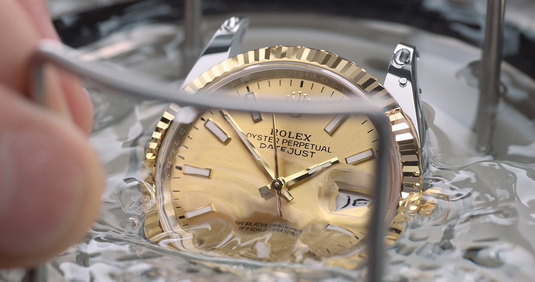 Eine Rolex Uhr ohne Armband wird auf Wasserdichtigkeit getestet und dafür in Behälter mit Wasser getaucht