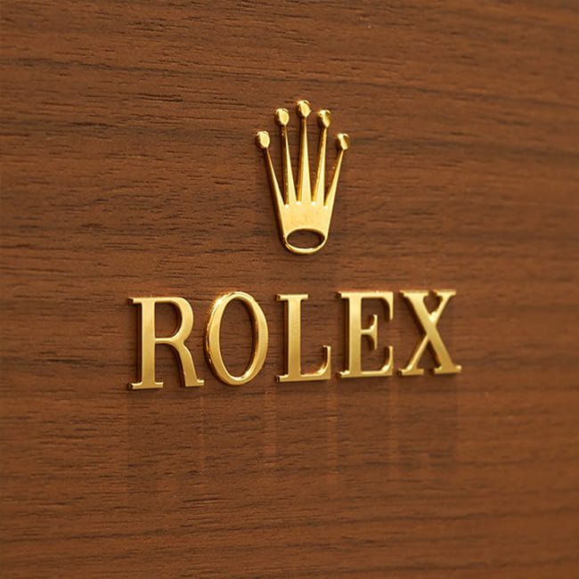 Ein großes goldenes Rolex Logo mit der Krone an einer holzvertäfelten Wand